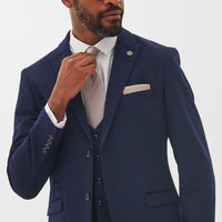 Man wearing sharp tailored navy blazer, tweaking tie.